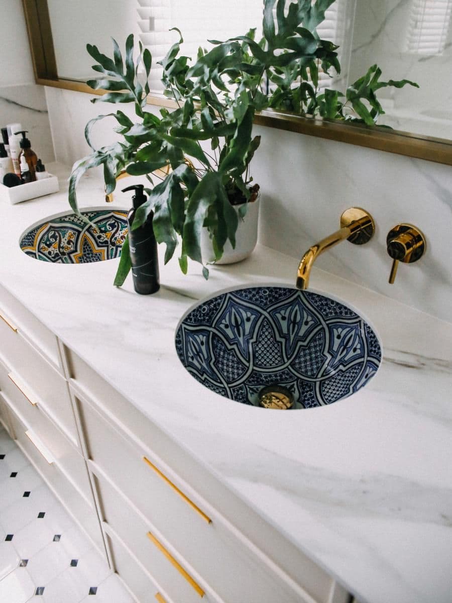 a bathroom with marble counter tops and gold faucets on the sink, along with plants in vases, classique, marbre