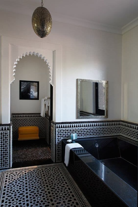 an ornate bathroom with black and white tiles on the floor, walls and bathtub, classique, zellige